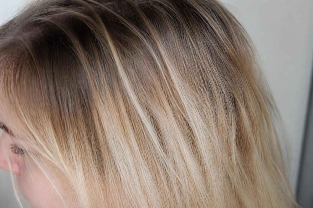 Zbliżenie blond włosów z jasnymi pasemkami i ciemniejszymi odrostami